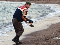 A paramilitary police officer carries the lifeless body of a  migrant child after a number of migrants died and a smaller number  were reported missing after boats carrying them to the Greek island of Kos capsized, near the Turkish resort of Bodrum early Wednesday, Sept. 2, 2015. (AP Photo/DHA) TURKEY OUT