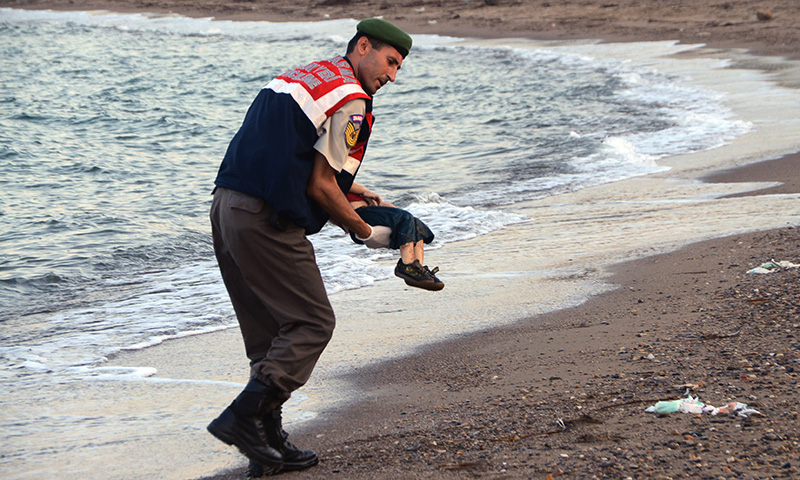 A paramilitary police officer carries the lifeless body of a  migrant child after a number of migrants died and a smaller number  were reported missing after boats carrying them to the Greek island of Kos capsized, near the Turkish resort of Bodrum early Wednesday, Sept. 2, 2015. (AP Photo/DHA) TURKEY OUT