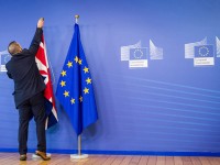An EU official hangs the Union Jack next to the European Union flag at the VIP entrance at the European Commission headquarters in Brussels on Tuesday, Feb. 16, 2016. British Prime Minister David Cameron is visiting EU leaders two days ahead of a crucial EU summit. (AP Photo/Geert Vanden Wijngaert)
