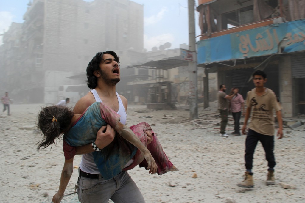 A man carries a young girl who was injured in a reported barrel-bomb attack by government forces on June 3, 2014 in Kallaseh district in the northern city of Aleppo. Some 2,000 civilians, including more than 500 children, have been killed in regime air strikes on rebel-held areas of Aleppo since January, many of them in barrel bomb attacks. AFP PHOTO / BARAA AL-HALABI        (Photo credit should read BARAA AL-HALABI/AFP/Getty Images)