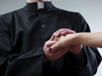 Priest holding believer hand