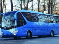 Modern blue bus is on the edge of the road.