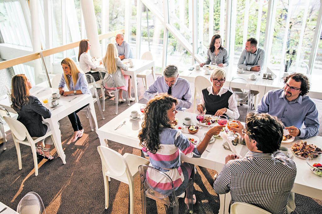 High angle view of large group of happy business people having lunch break in cafeteria and communicating among themselves.