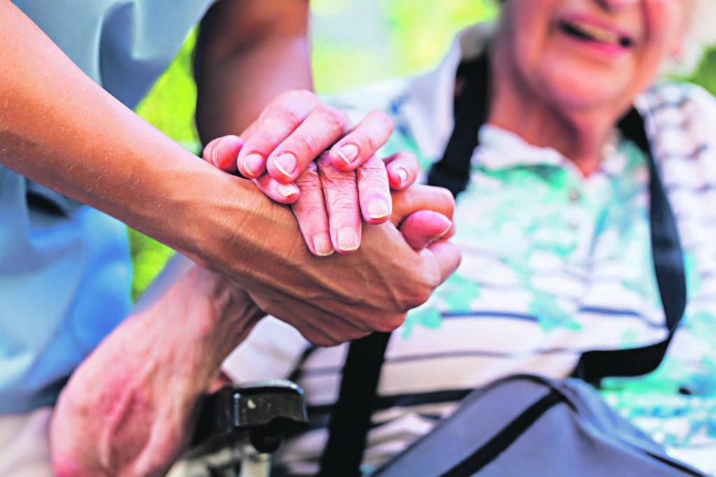 Nurse consoling senior woman holding her hand
