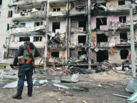 A police officer stands guard at a damaged residential building at Koshytsa Street, a suburb of the Ukrainian capital Kyiv, where a military shell allegedly hit, on February 25, 2022. - Invading Russian forces pressed deep into Ukraine as deadly battles reached the outskirts of Kyiv, with explosions heard in the capital early Friday that the besieged government described as "horrific rocket strikes". The blasts in Kyiv set off a second day of violence after Russian President Vladimir Putin defied Western warnings to unleash a full-scale ground invasion and air assault that quickly claimed dozens of lives and displaced at least 100,000 people. (Photo by GENYA SAVILOV / AFP)