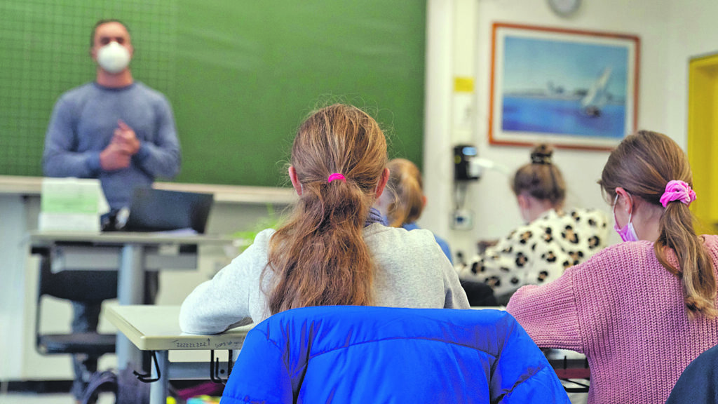 08.11.2021, Bayern, Würzburg: Schülerinnen und Schüler der Klasse 5c des Matthias-Grünewald-Gymnasiums in Würzburg sitzen mit Mund-Nasen-Schutz im Klassenzimmer. In Bayern beginnt die Schule nach den Herbstferien mit neuen Corona-Regeln. Foto: Nicolas Armer/dpa - ACHTUNG: Nur zur redaktionellen Verwendung im Zusammenhang mit der aktuellen Berichterstattung über den ersten Schultag nach den Herbstferien in Bayern. +++ dpa-Bildfunk +++